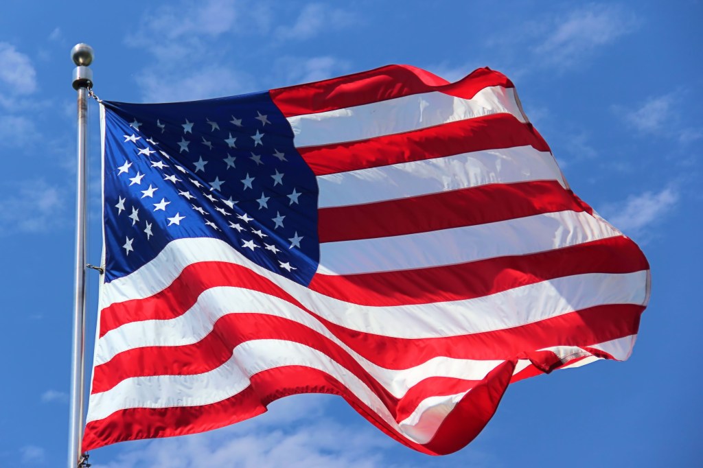 American flag waving against a blue sky.